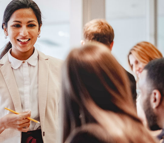 A professional woman in a business suit giving a presentation to a group of people in a corporate setting.