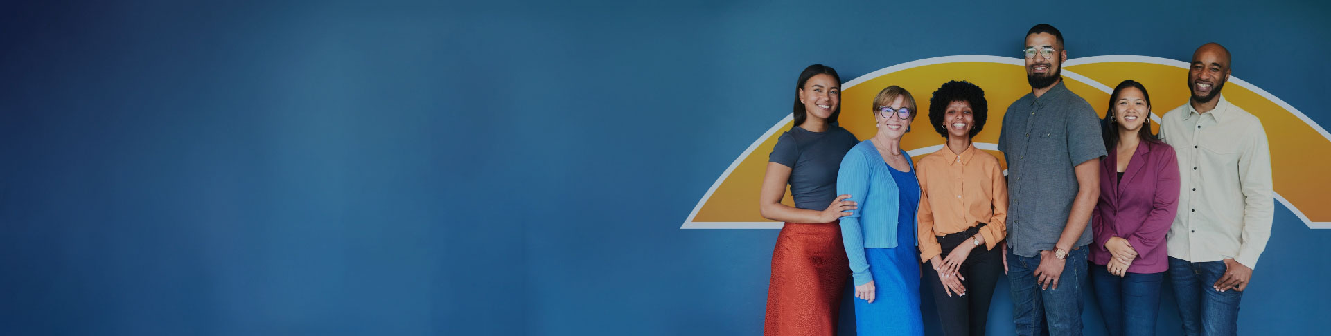 Multicultural crowd posing in front of a blue and yellow logo.